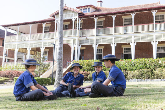 Four Churchie boarders sitting on the grass in front of School House